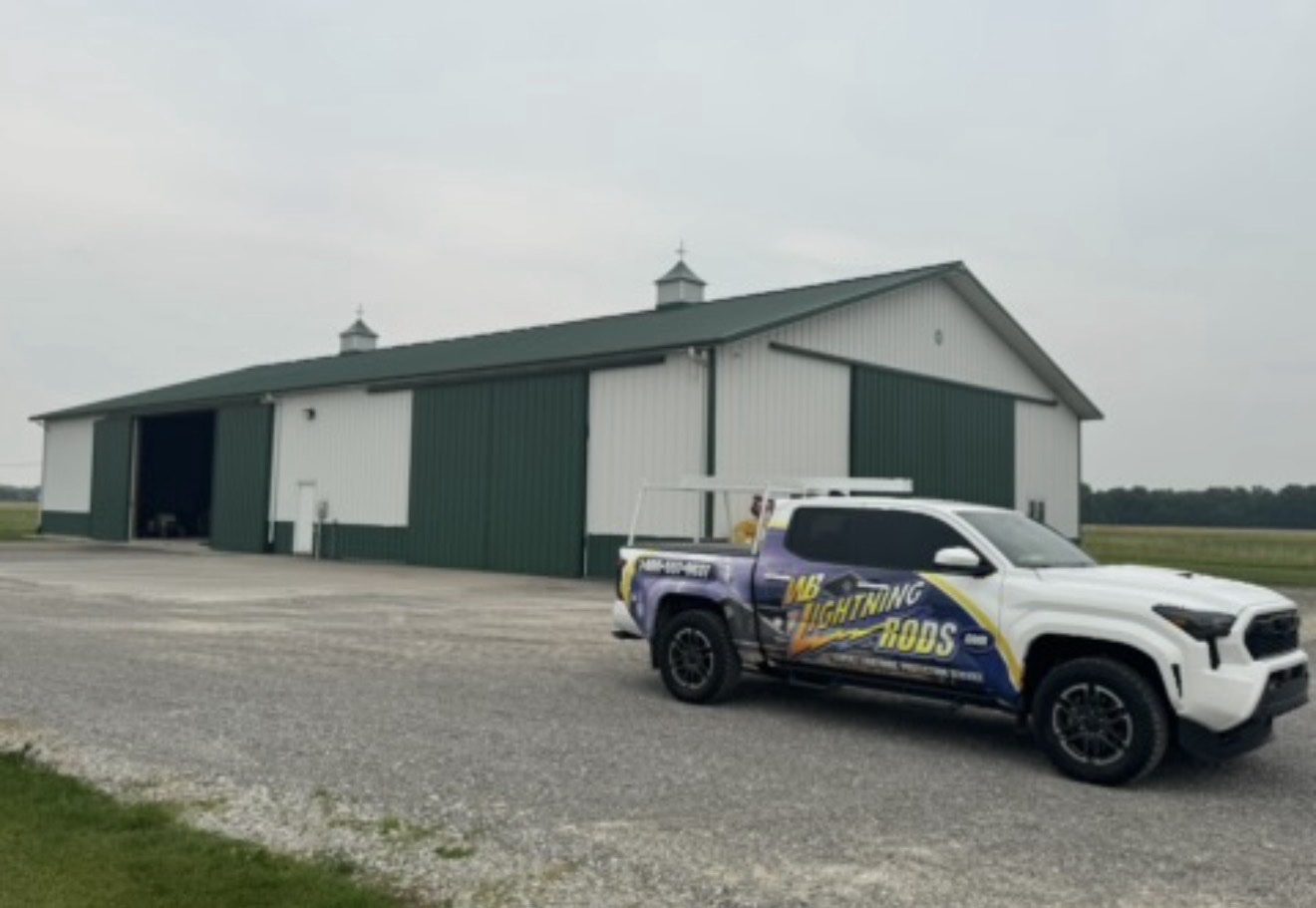 Green and white pole barn with the WB Lightning Rods truck parked in front